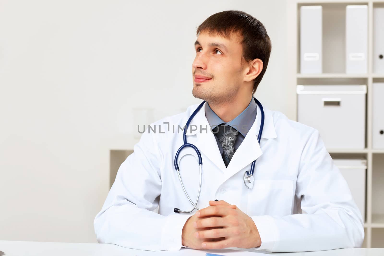 Young male doctor in white uniform at workplace