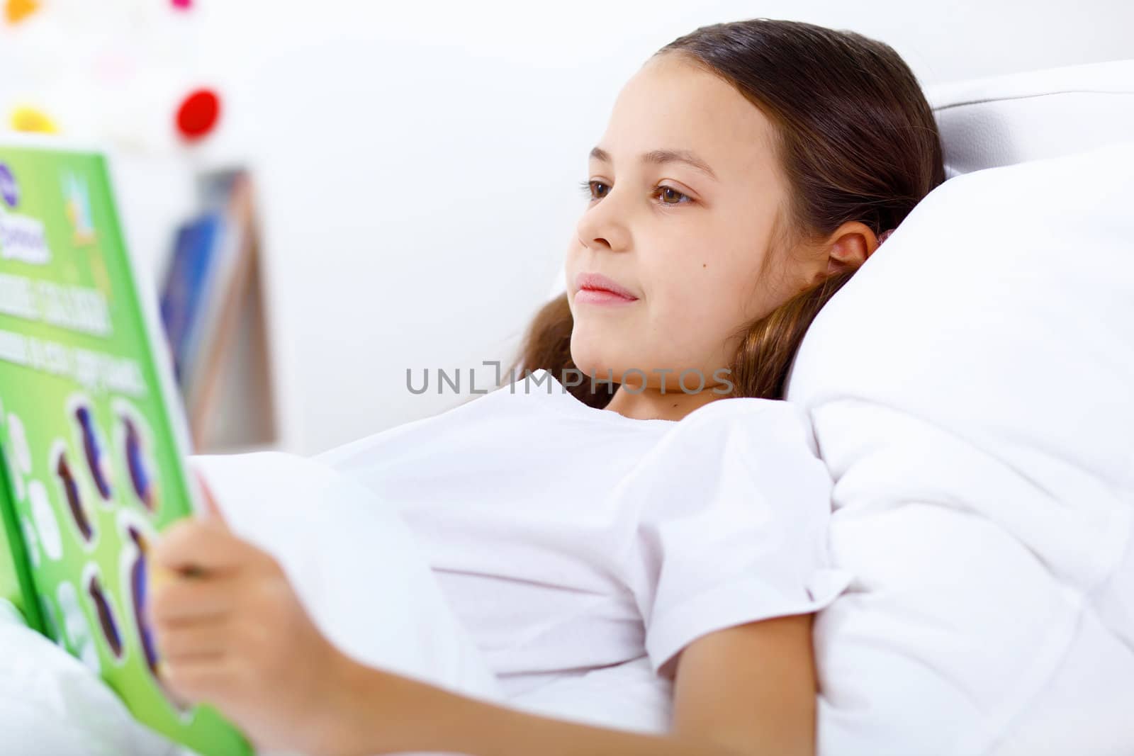 Portrait of girl with a book in bed at home