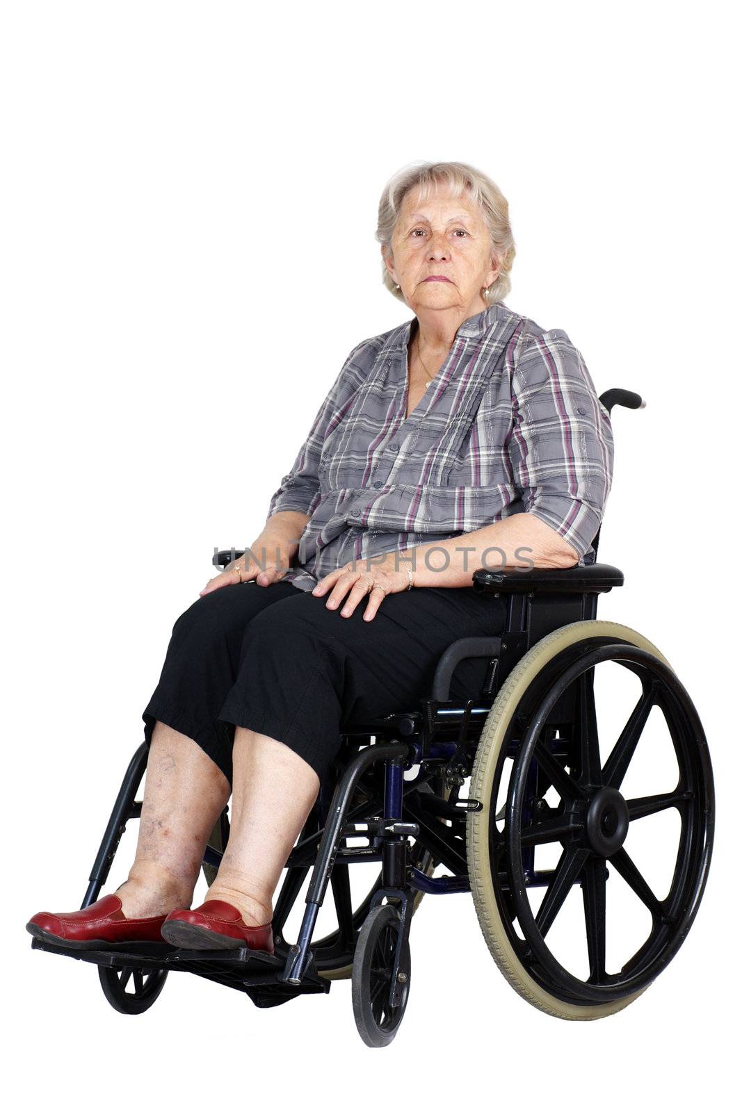 Sad or depressed senior woman in a wheelchair, looking down, studio shot isolated over white background.