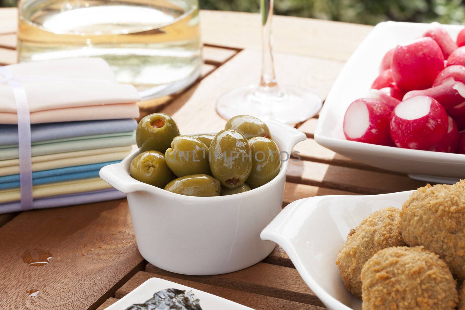 Green olives stuffed with red pimento in small white bowl.