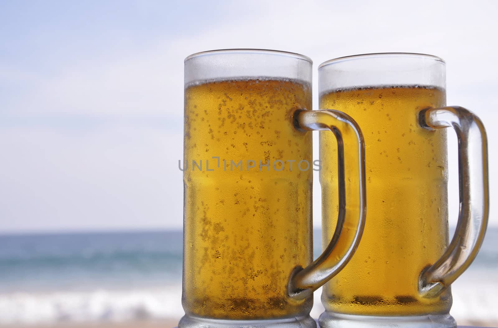 Two mugs of chilled Beer on a sunny day at the beach