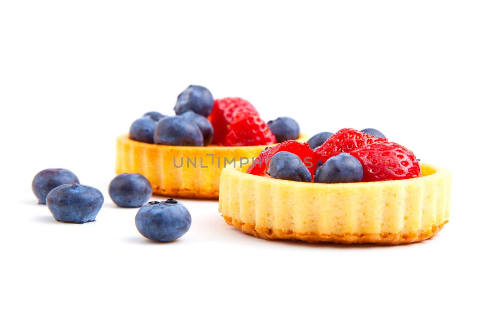 dessert fruit cake with strawberries and blueberries, over a white background.