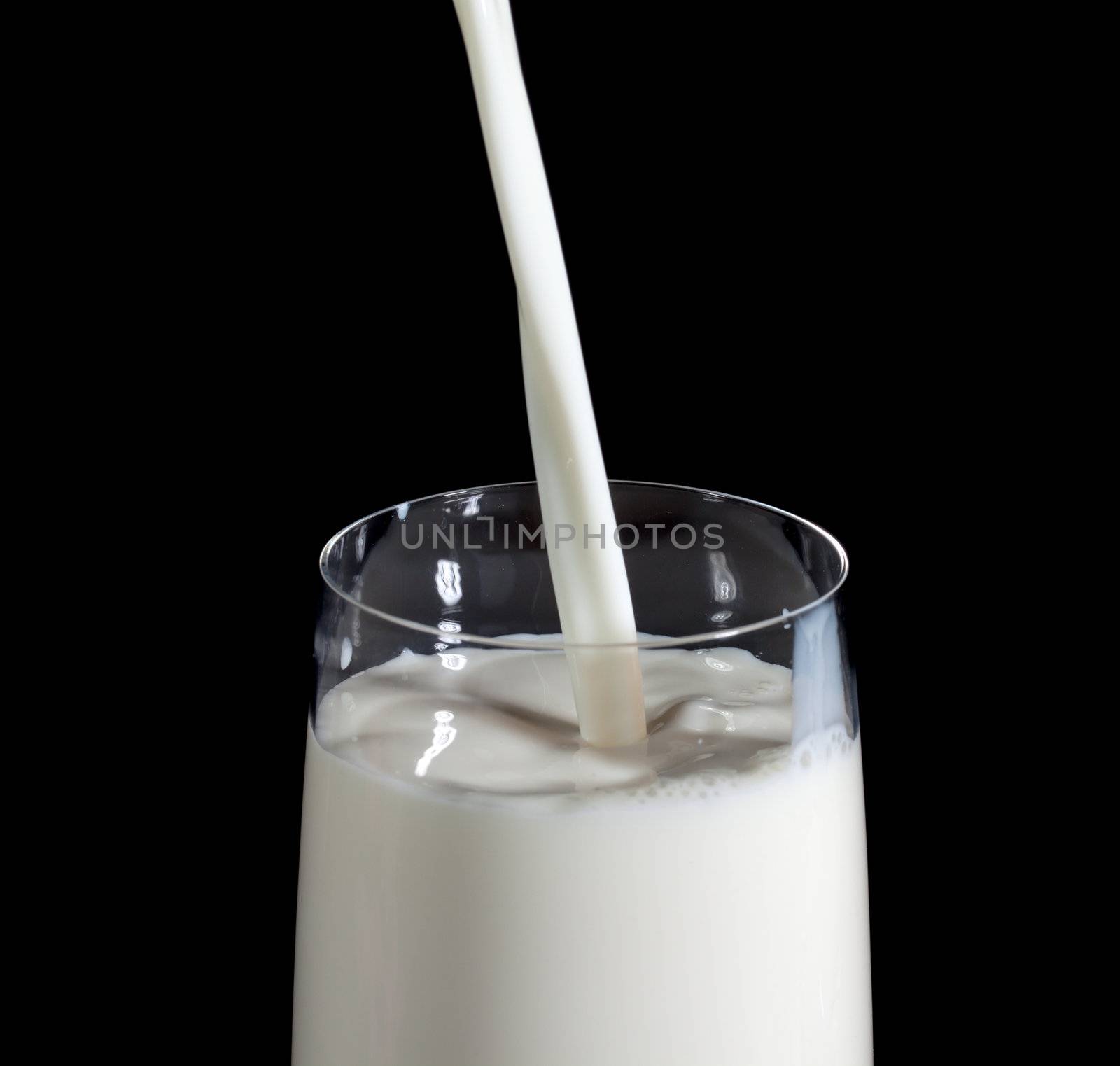 Pouring Milk in Glass, on black background