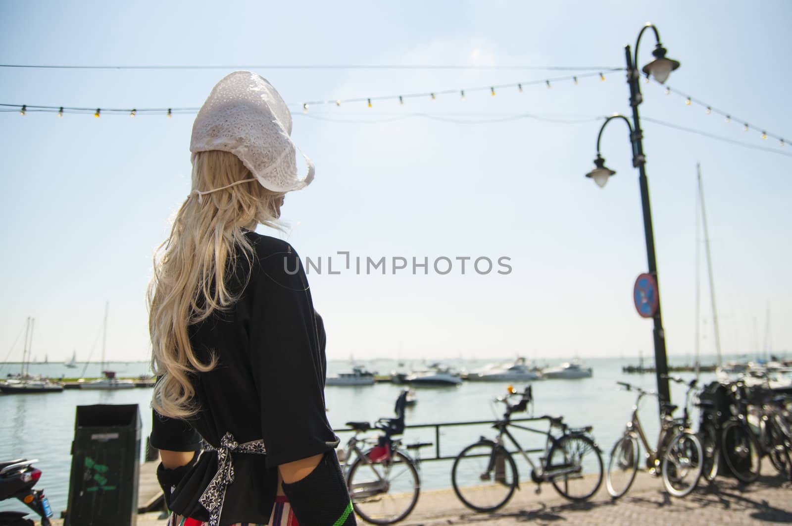 Female mannequin dressed in traditional dutch outfit with blurred coastal background.