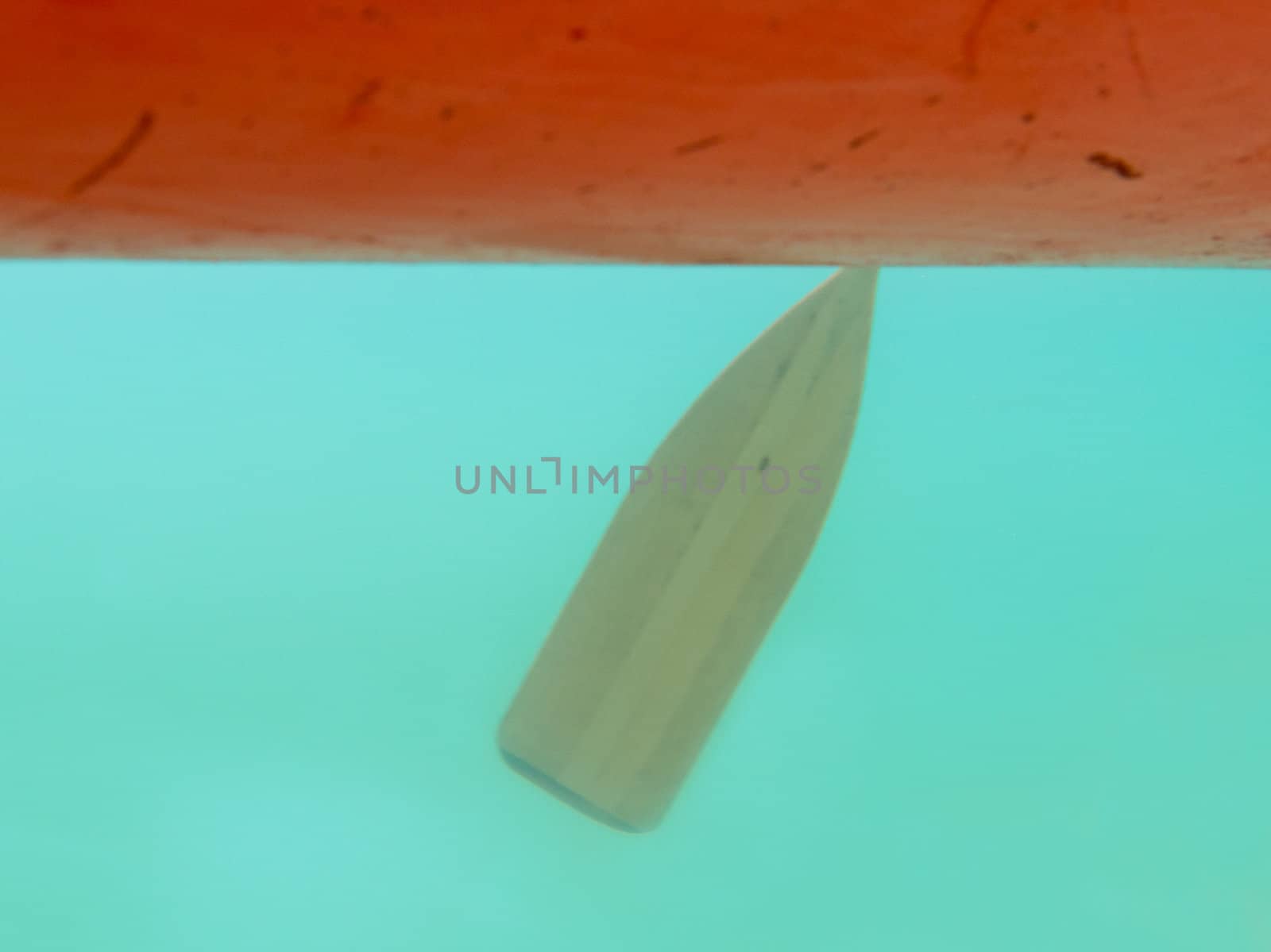 Red canoe, paddle in the water seen from underwater.