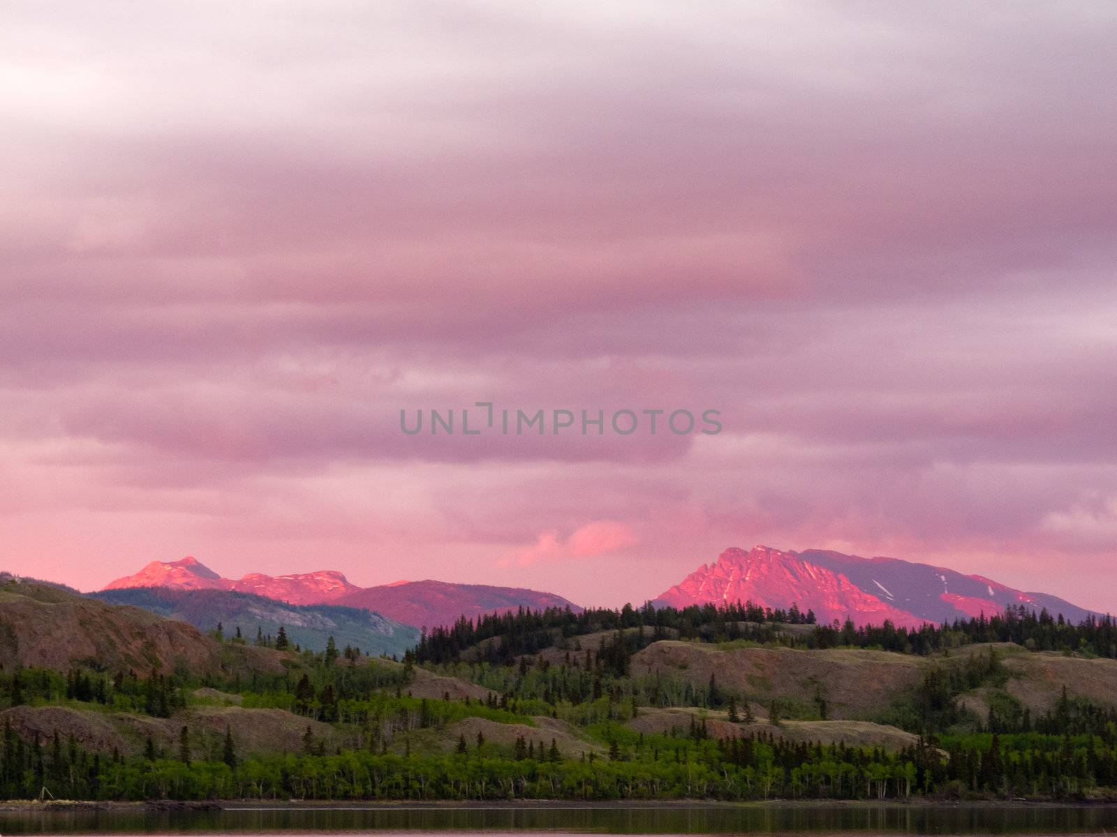 Distant mountains glowing in sunset light at Lake Laberge, Yukon Territory, Canada.