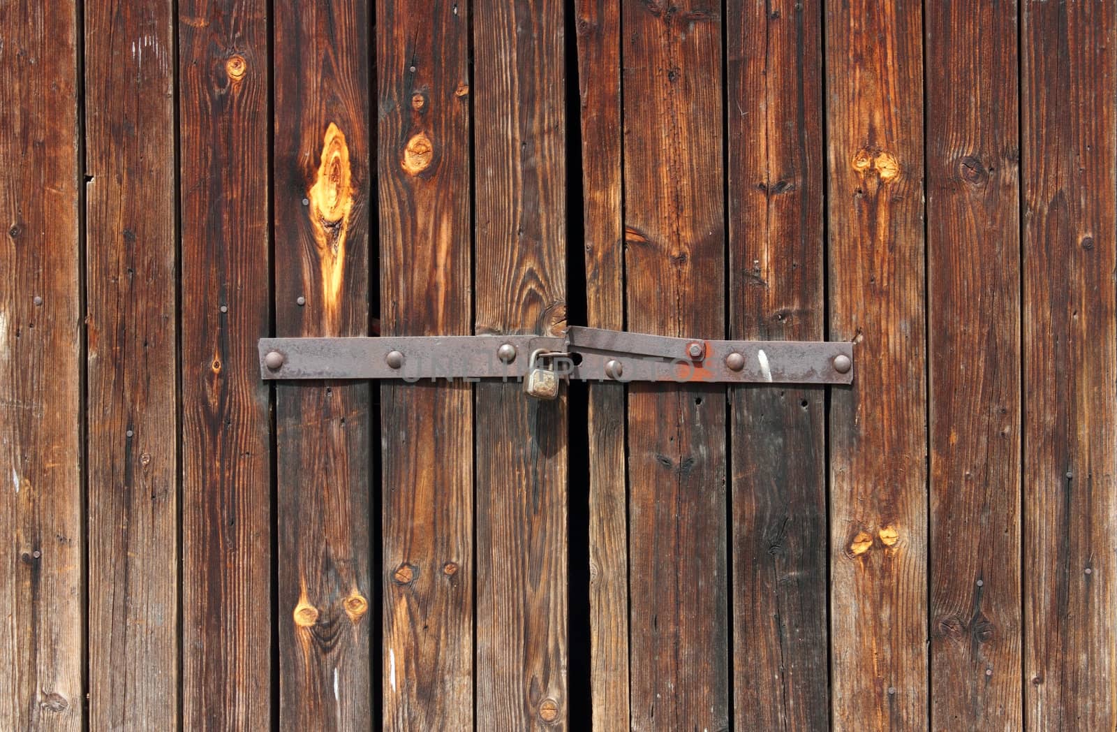Old Wooden door locked with rusty padlock background.