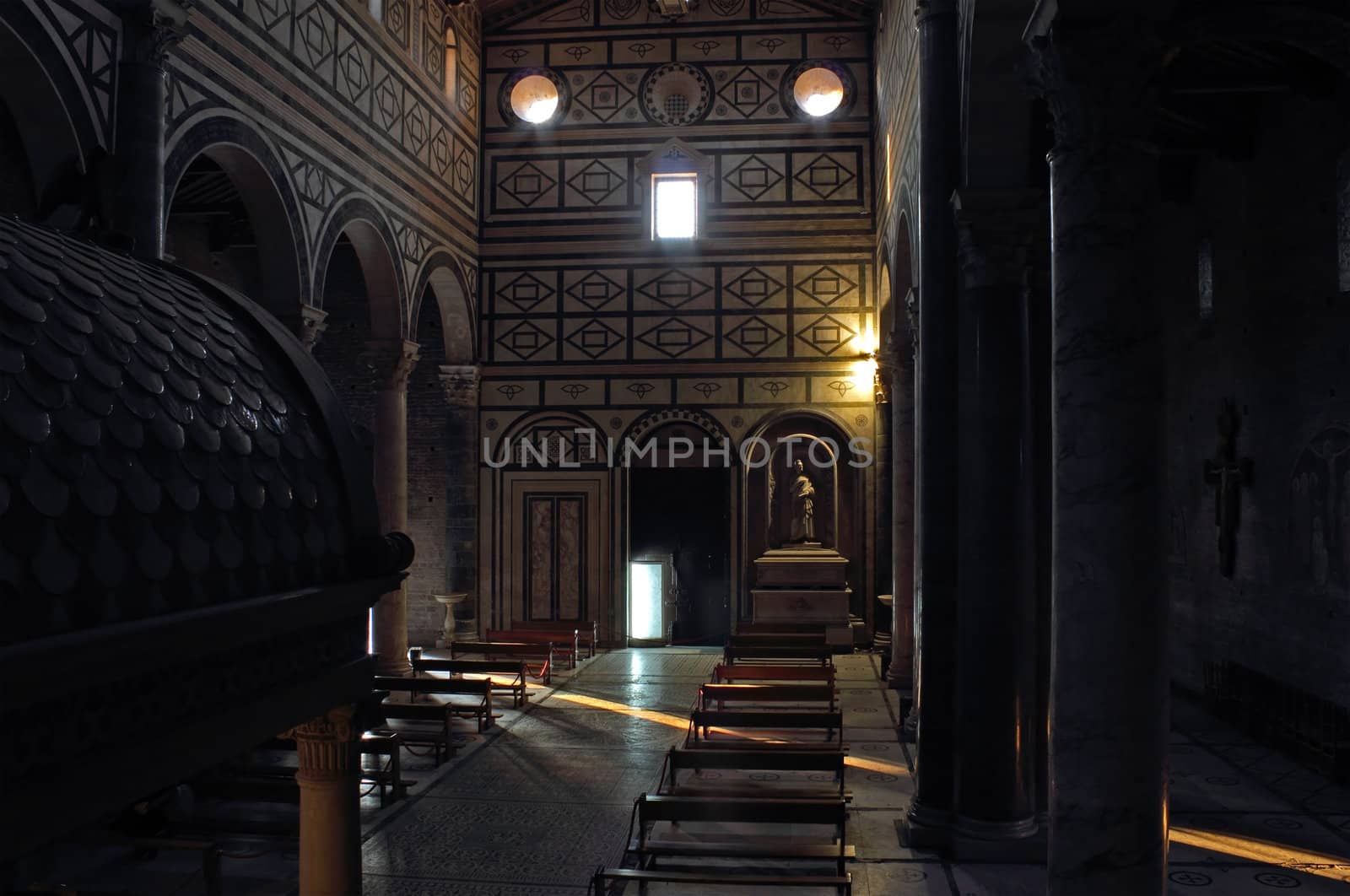 San Miniato al Monte in Florence church interior with warm light coming through the door and windows.