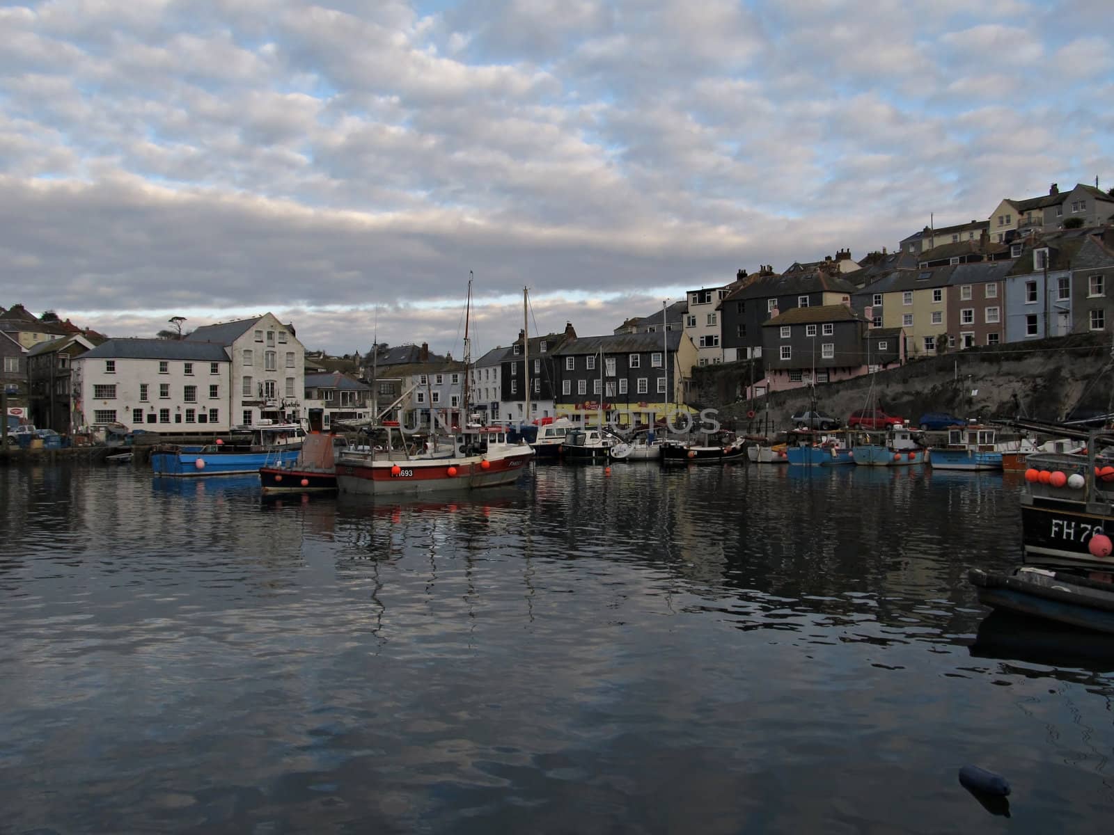 Mevagissey Harbor in the morning light with fishing boats and sky reflection in the water.