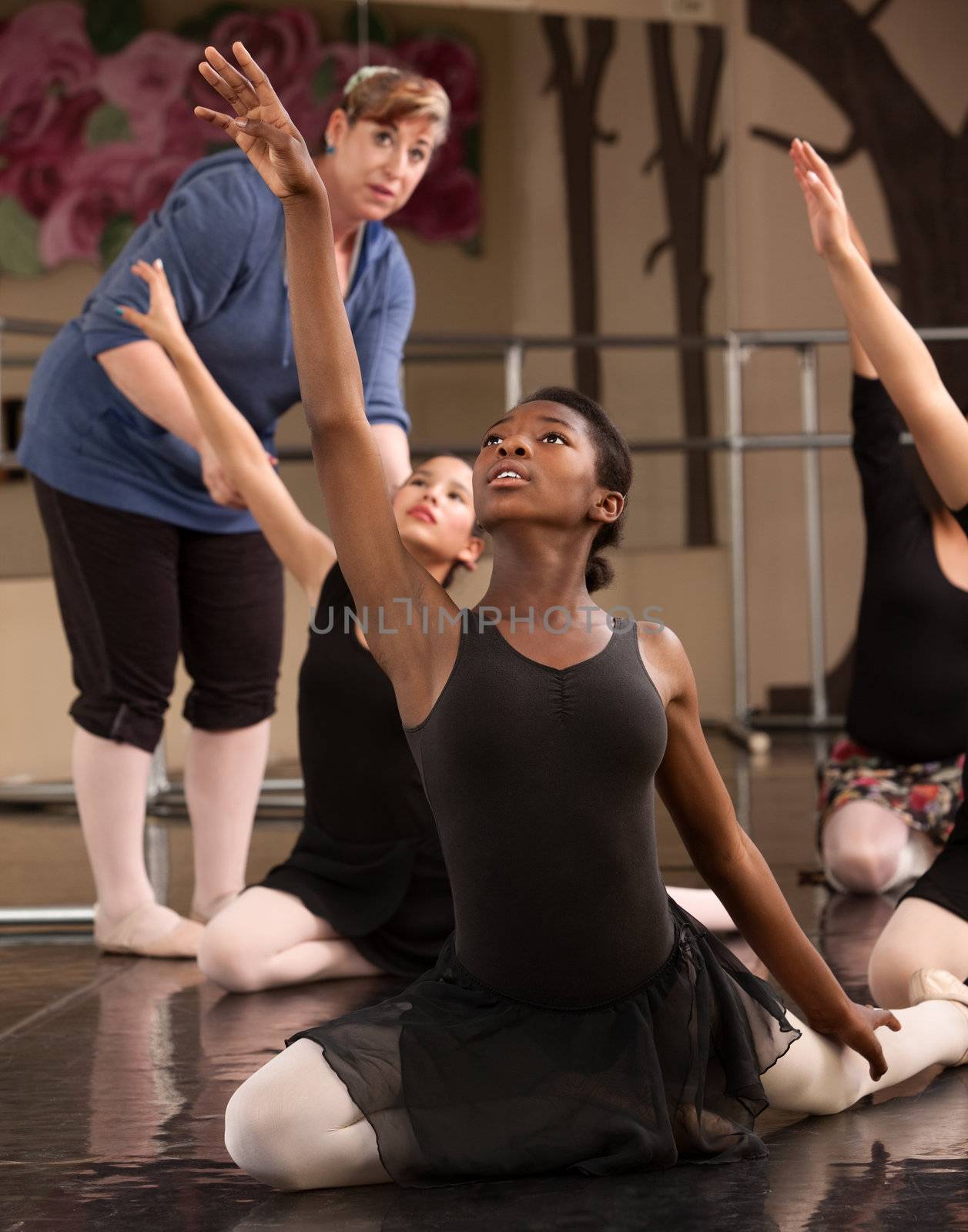 Ballet class teacher helps students practice dance moves