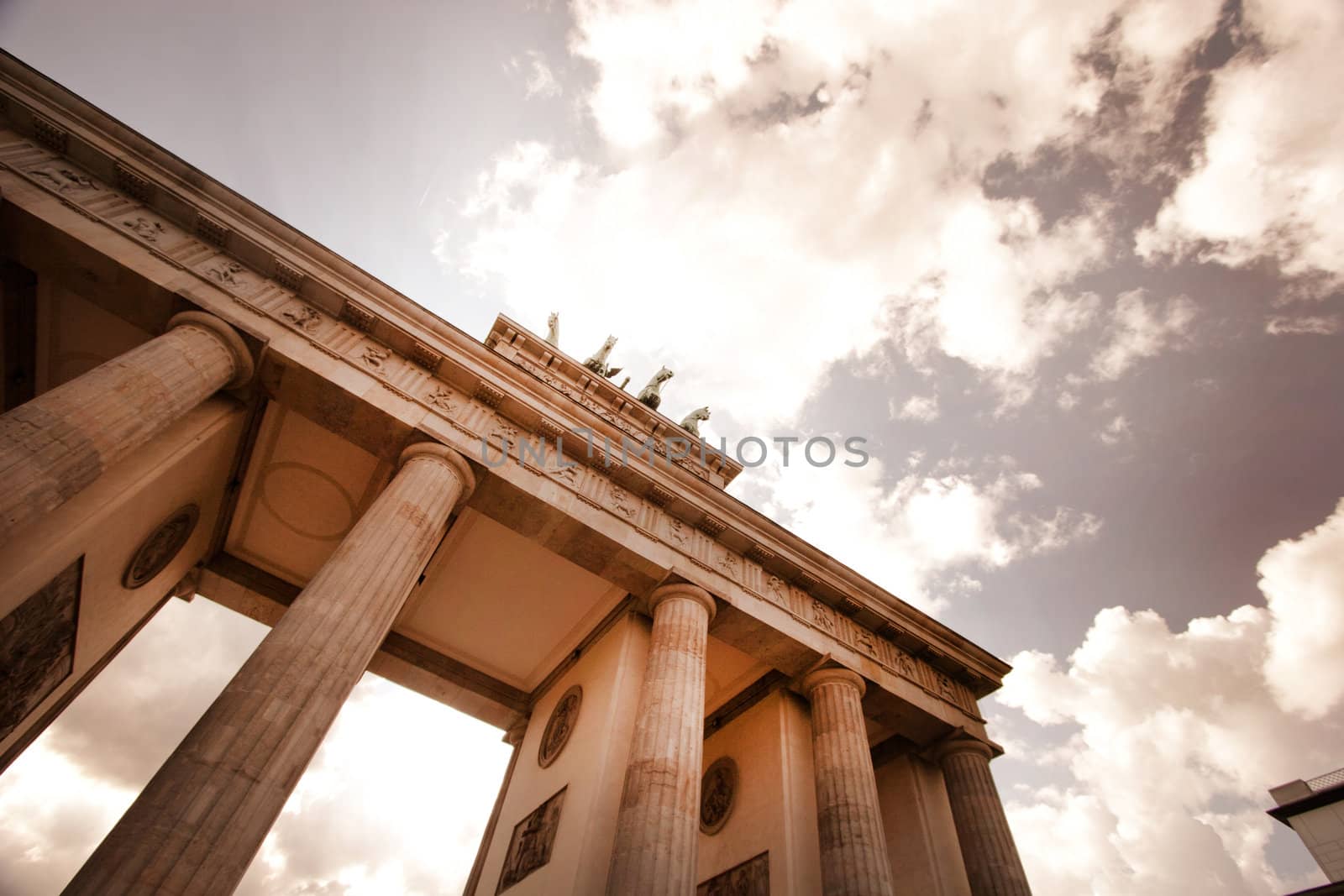 Low angle view looking up the stonework of the Brandenberg Gate in Berlin towards the statue of the Quadriga on the top against a cloudy sky