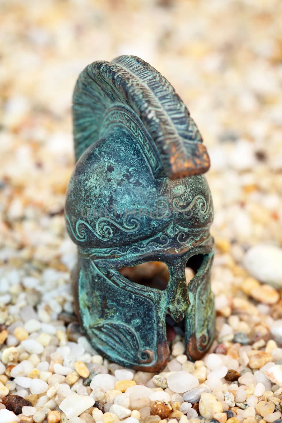 ancient bronze greek helmet placed on coarse sand