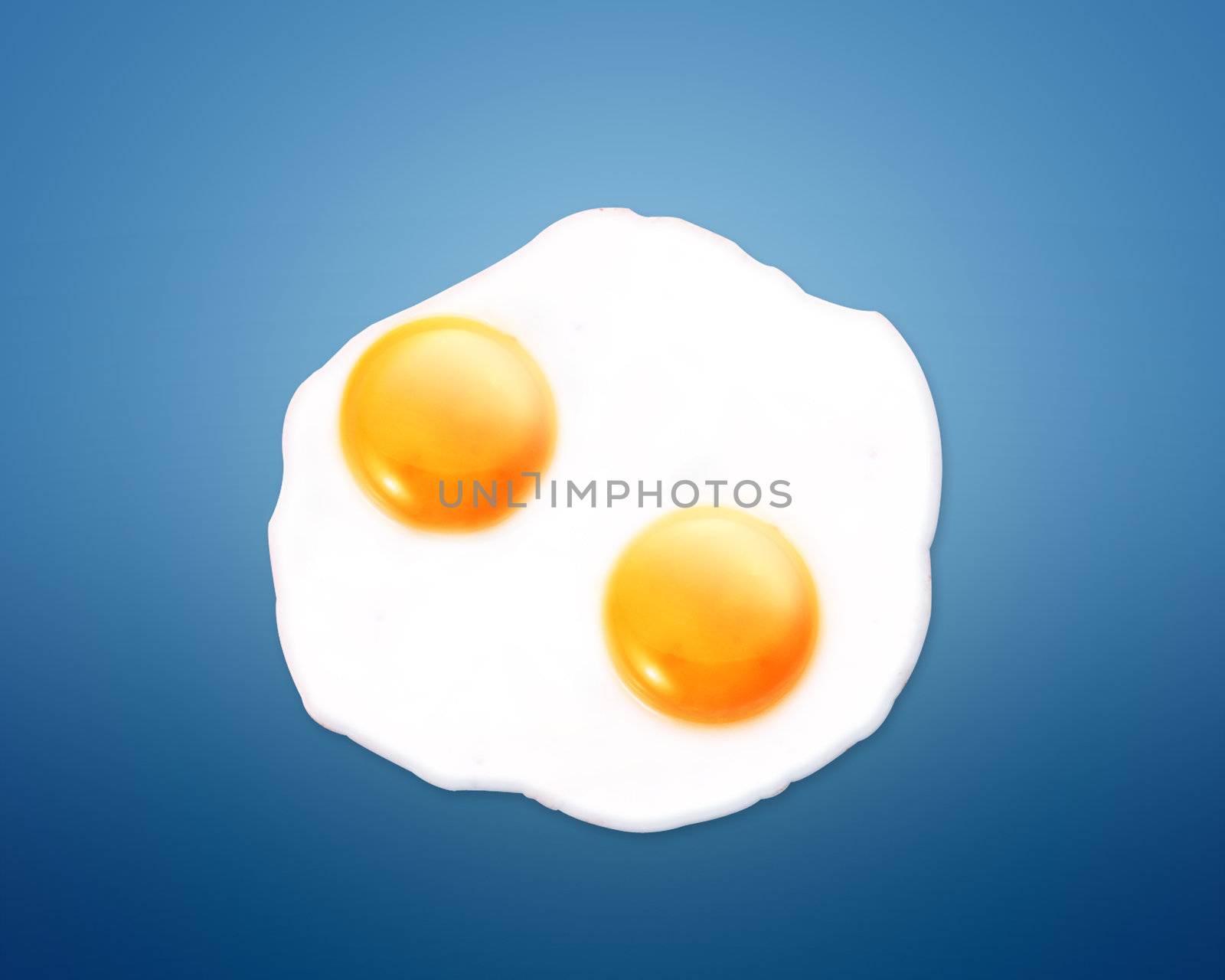 top view of two fried eggs on orange background.