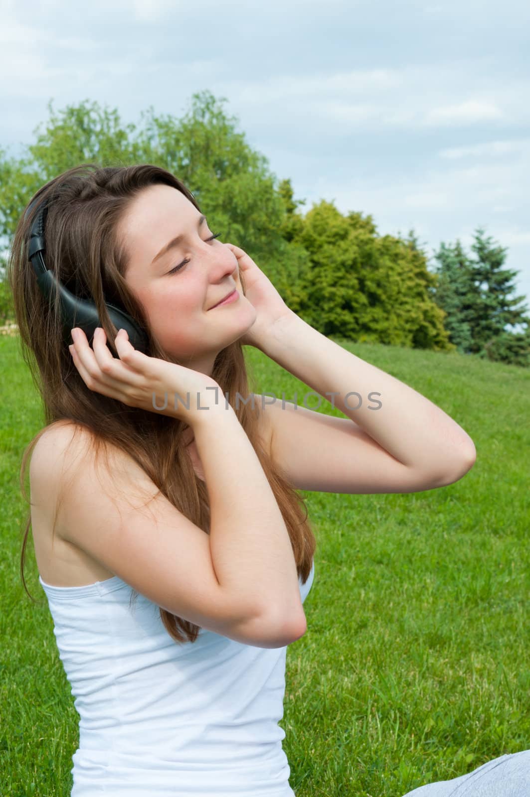 Girl in headphones listens to music in park.