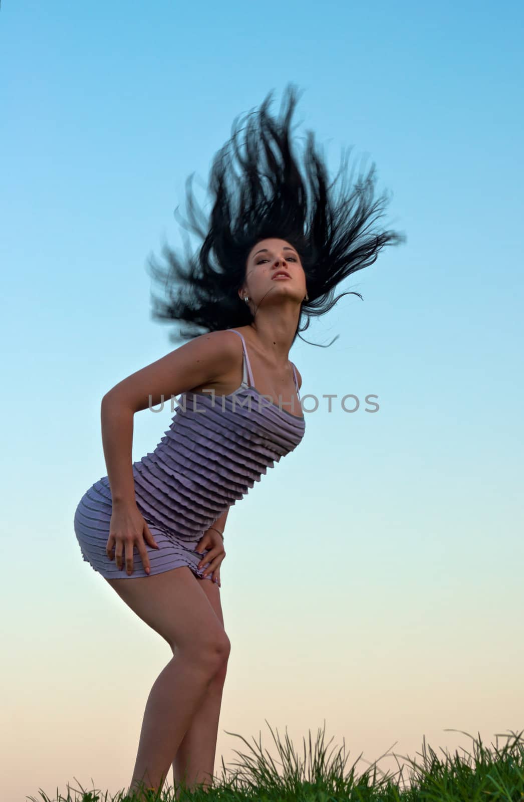 Girl with disheveled hair against evening sky.