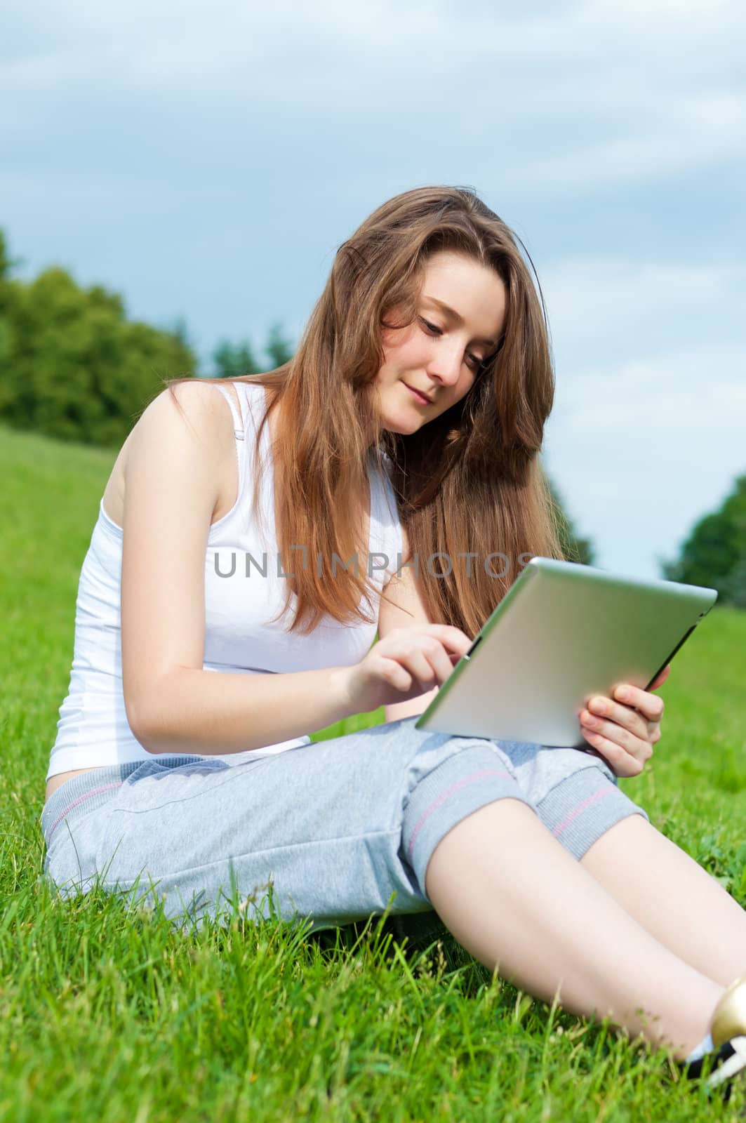 Girl with tablet in park on grass. by BPhoto