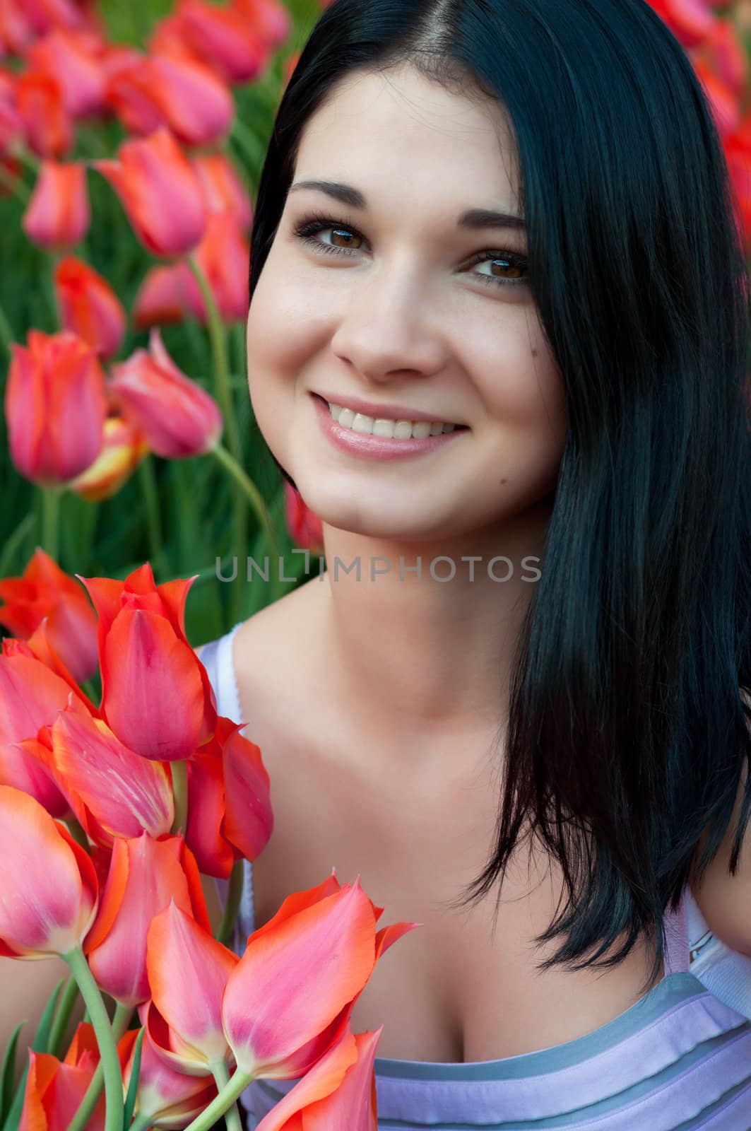 Brunette girl close-up with bright red tulips.