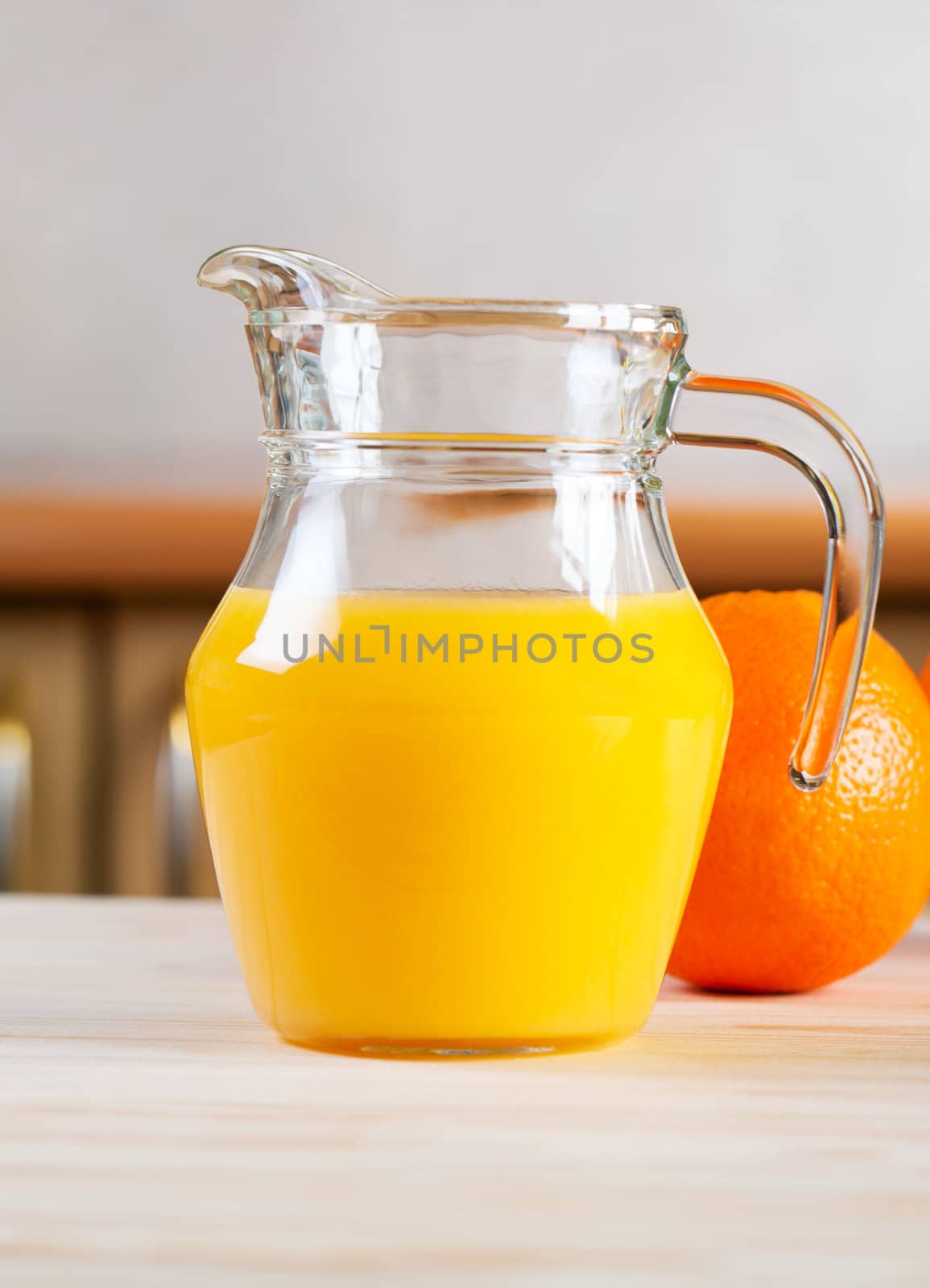 Juice in glass jar and orange on kitchen table.