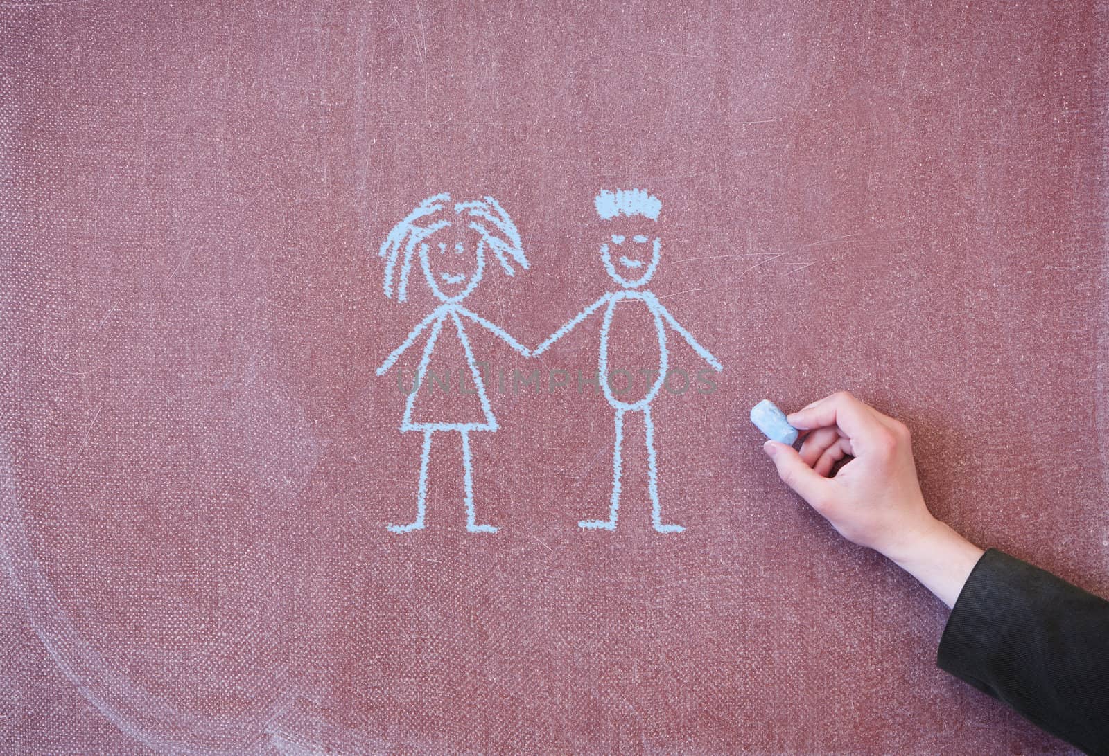 Boy and girl holding hands. Drawing with chalk on blackboard.