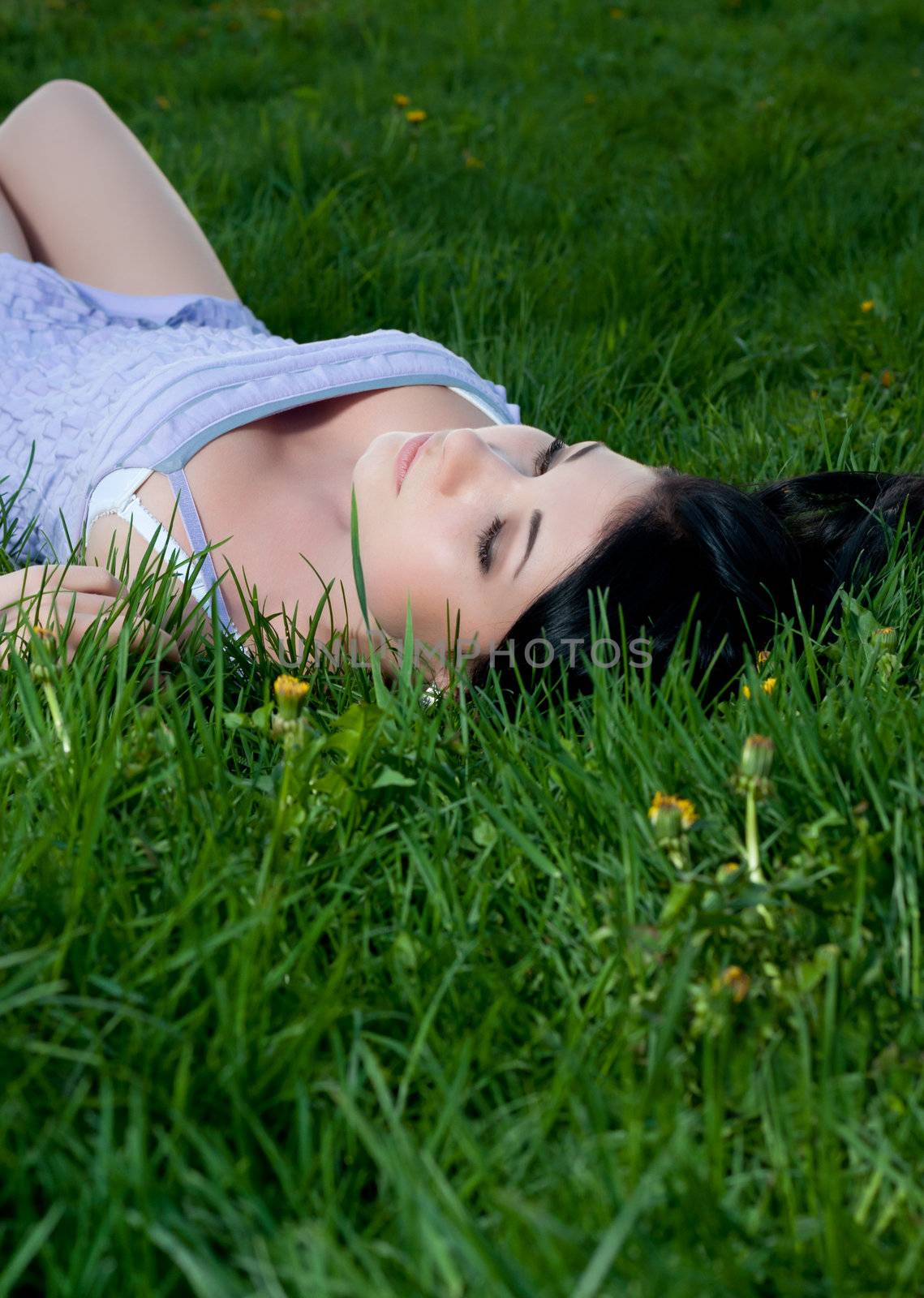 Woman lies on her back in grass at night.