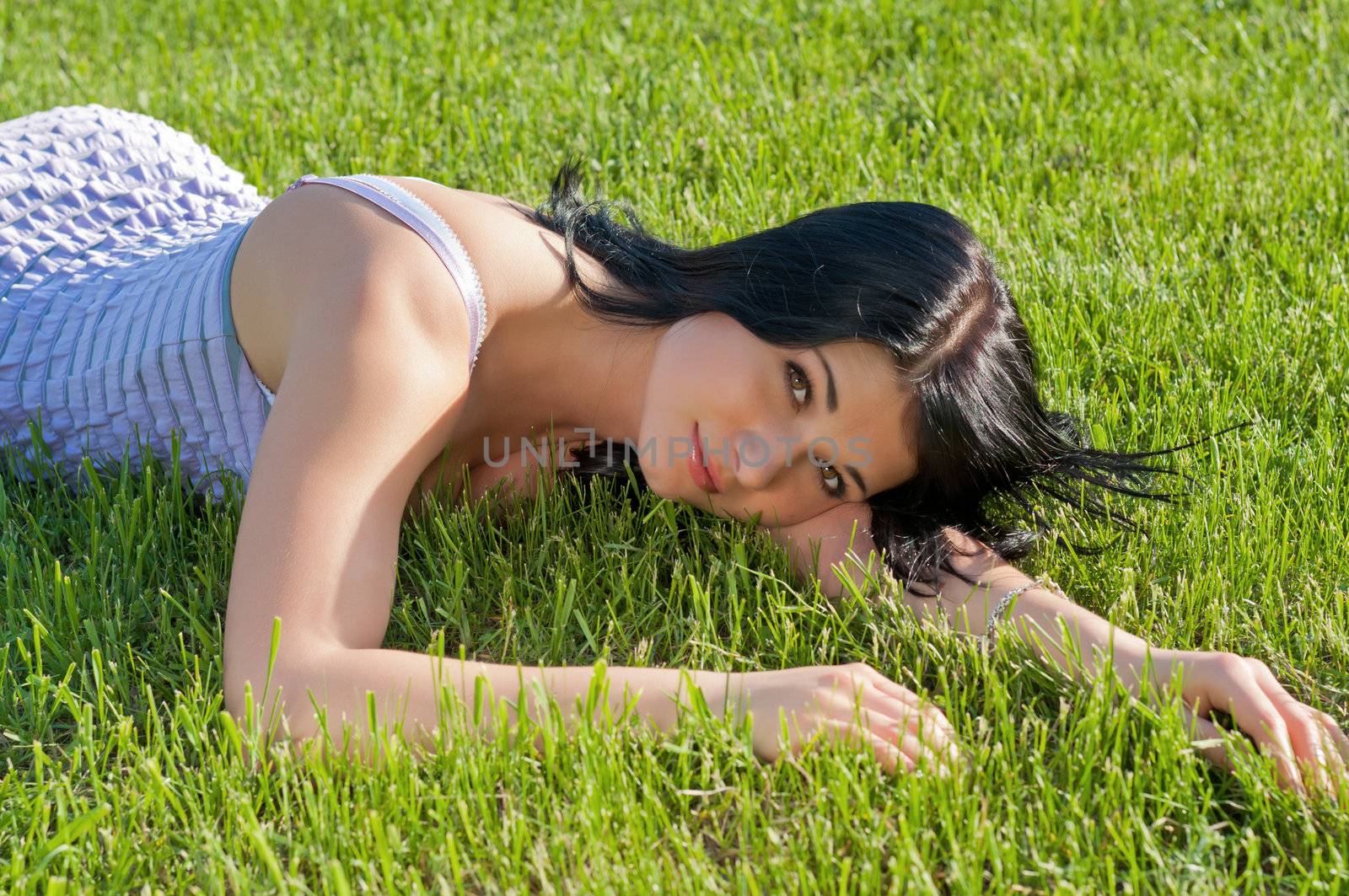 Beautiful girl lying on grass on bright sunny day.