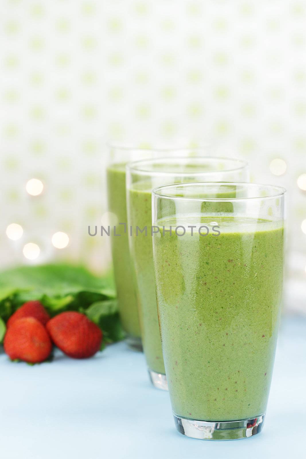 Delicious freshly made Spinach and Strawberry smoothies made with cold milk, yogurt, spinach and strawberries. Extreme shallow depth of field with selective focus on glass in foreground.
