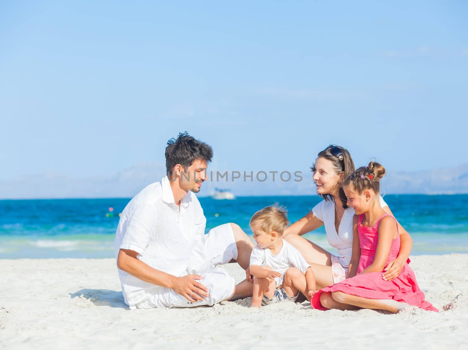 Family of four on tropical beach by maxoliki