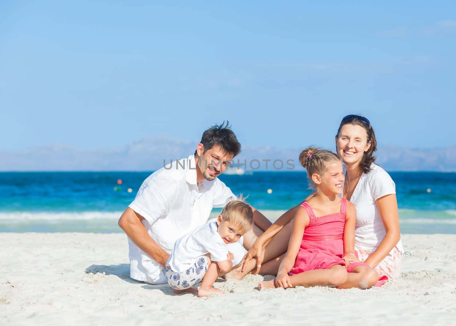 Family of four on tropical beach by maxoliki