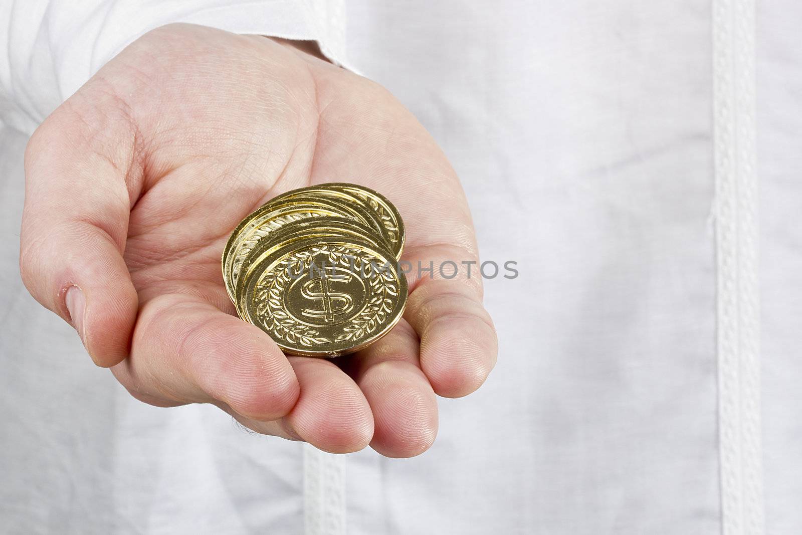 Close-up photograph of a man's hand holding a stack of coins.