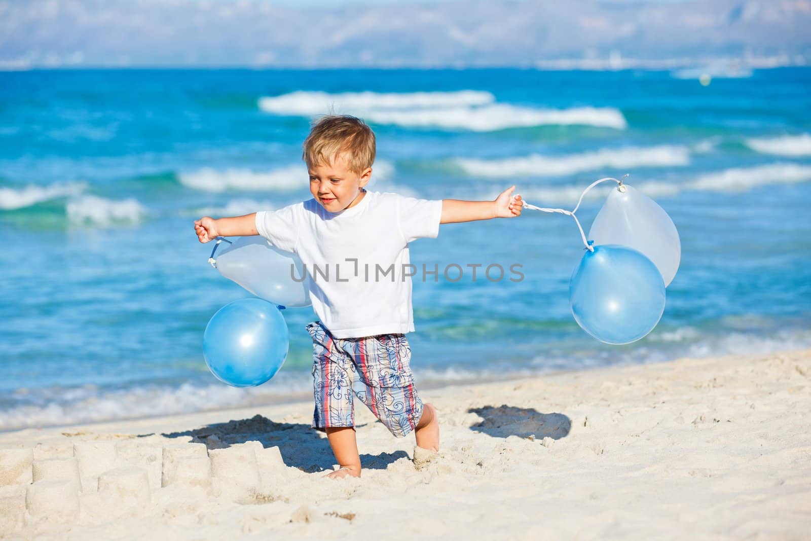 Cute little boy plays with ballons on the beach
