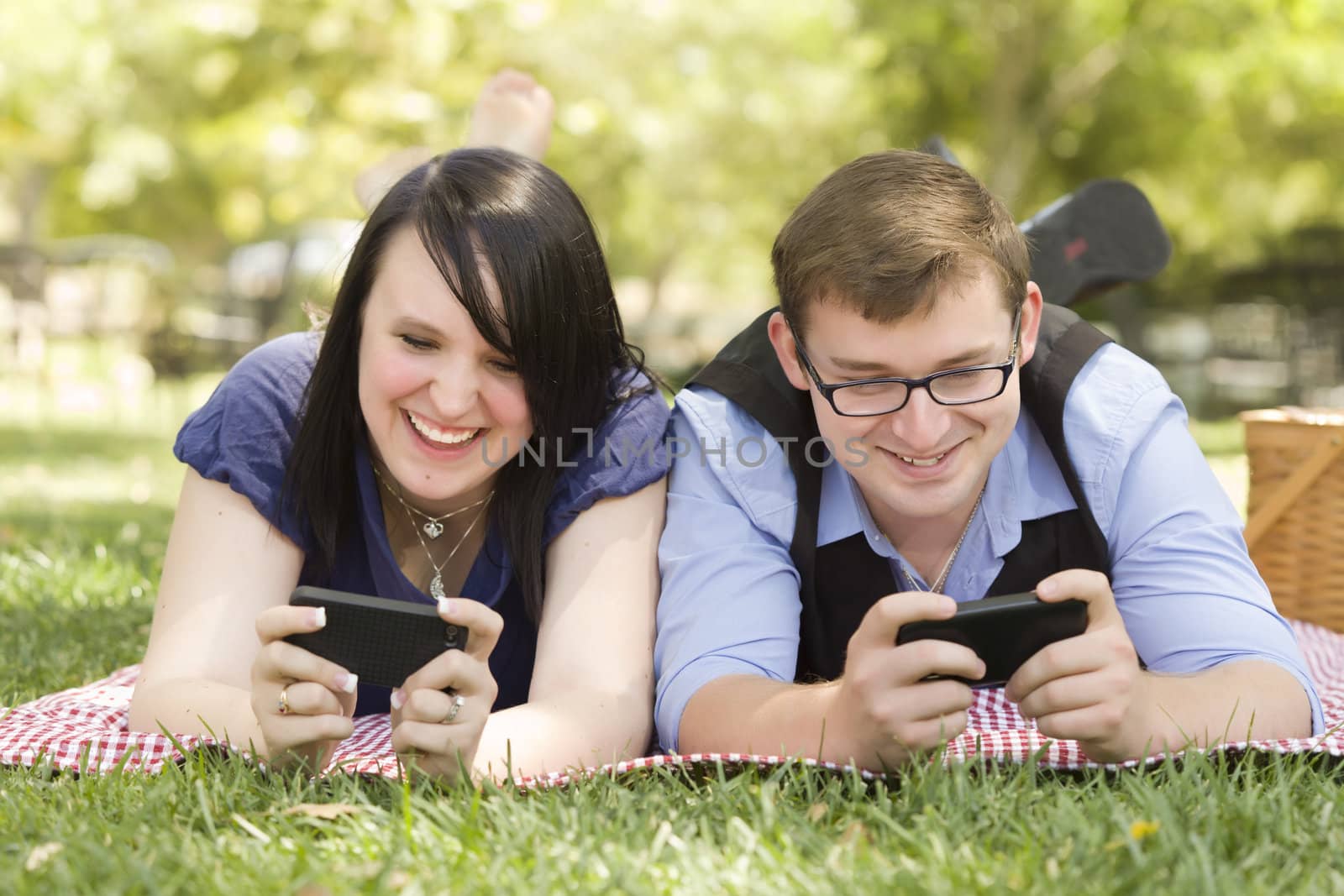 Attractive Young Couple at the Park Texting on Their Smart Phones Together.