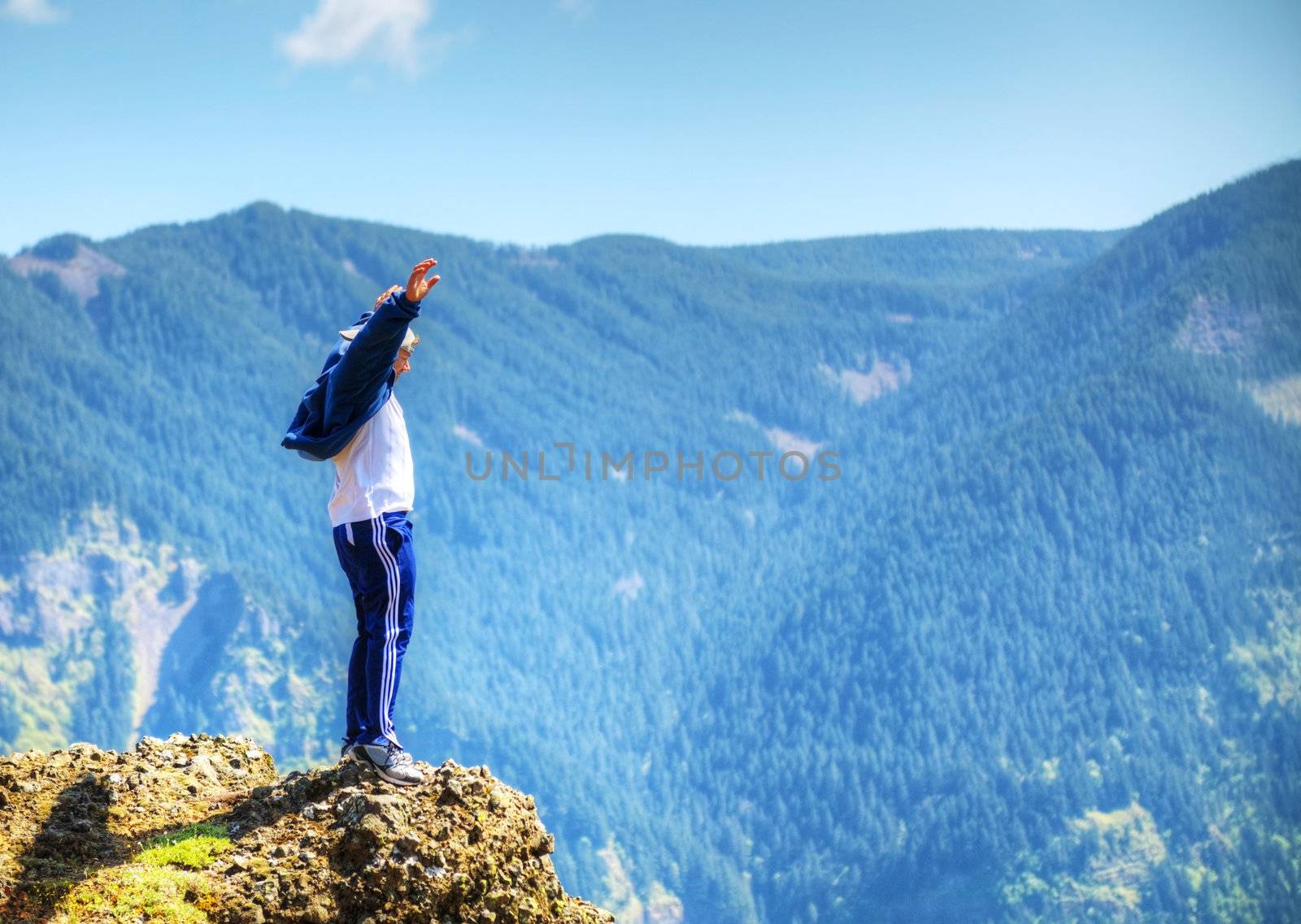 Man staying at the edge of the rock against mountain range