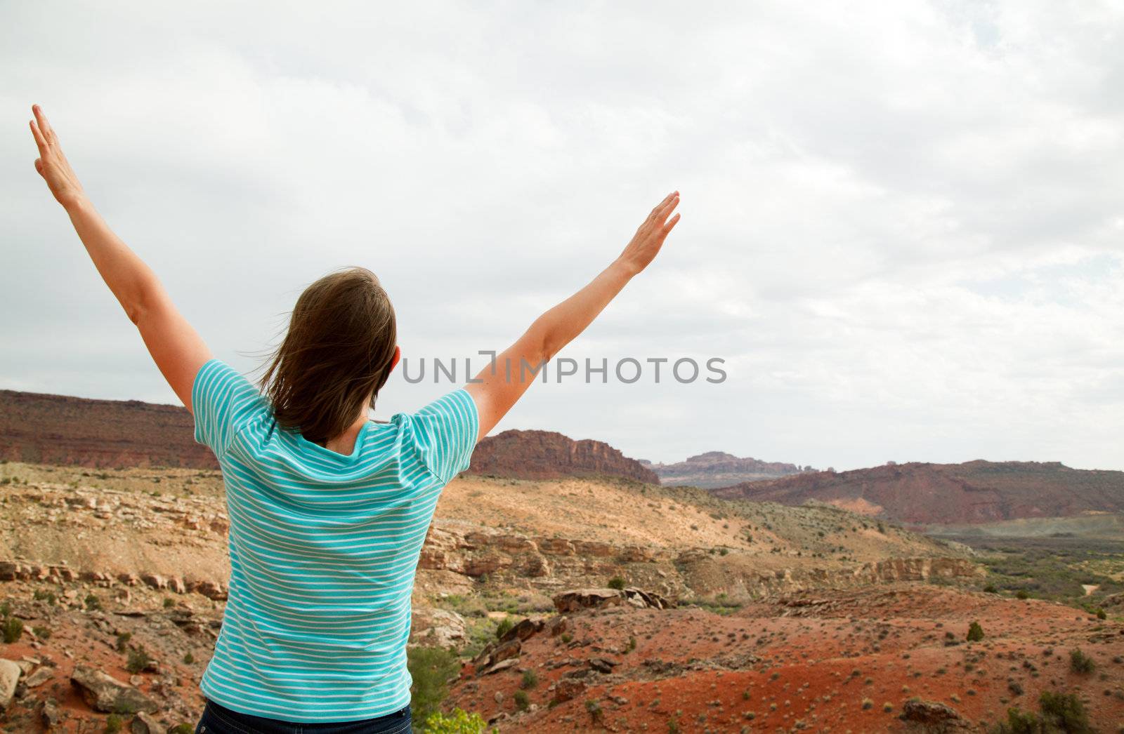 Woman with raised hands against cloudy sky