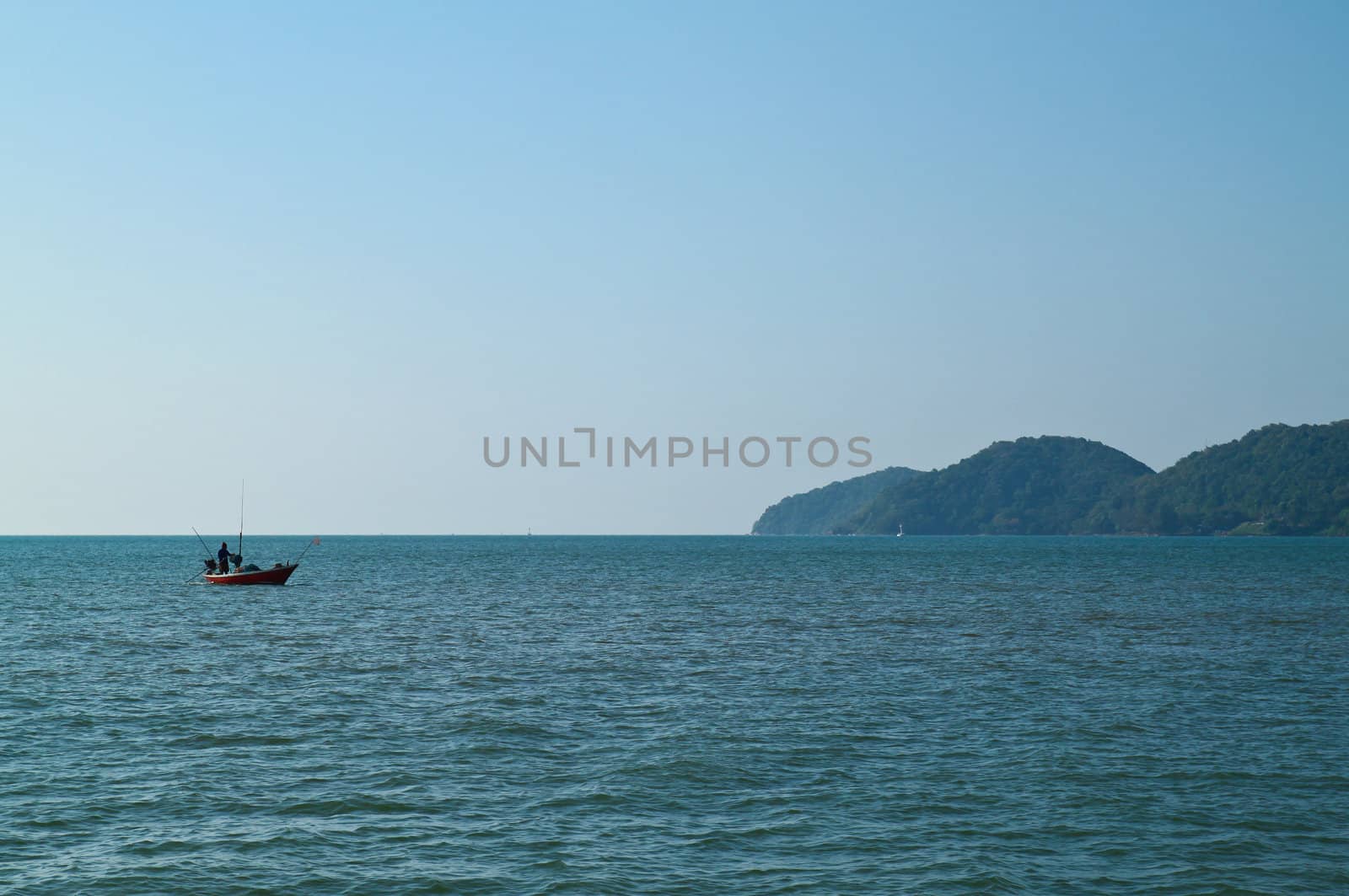 The silhouette of a fisherman with his boat in the sea by nuchylee