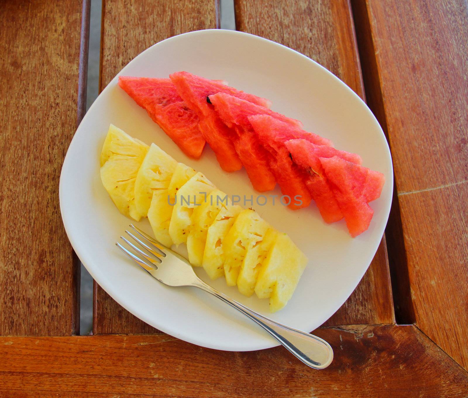 Watermelon and pineapple on dish with fork by nuchylee