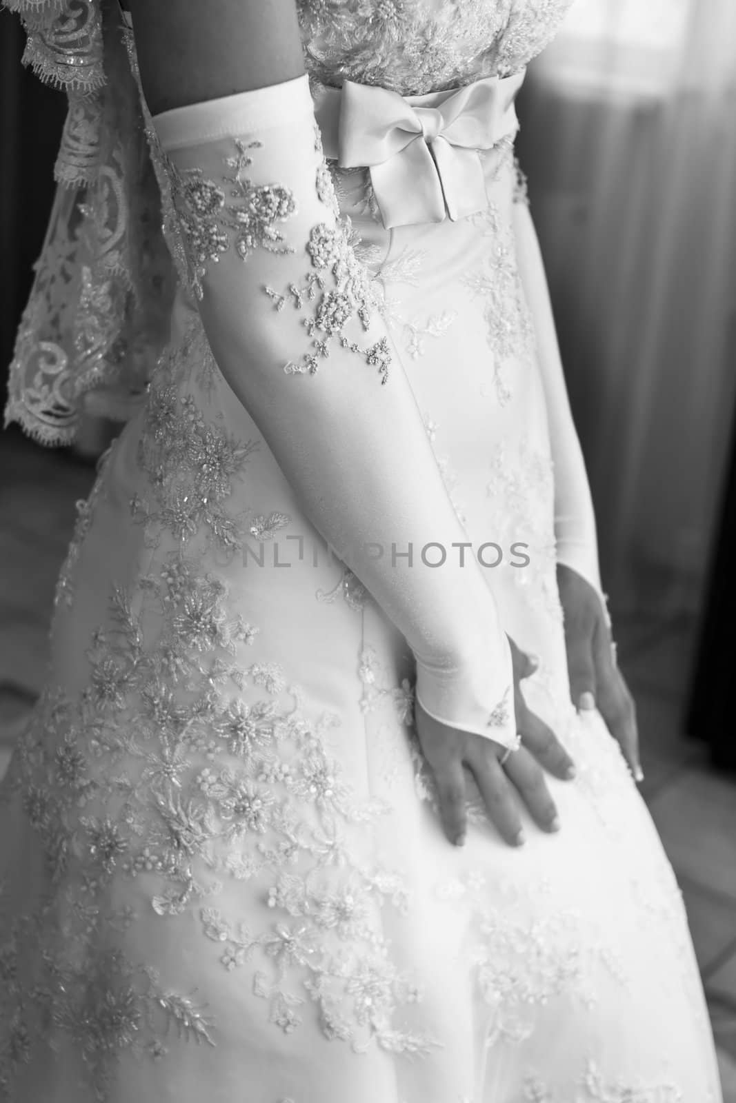 The bride in a beautiful dress with a veil stands at the window