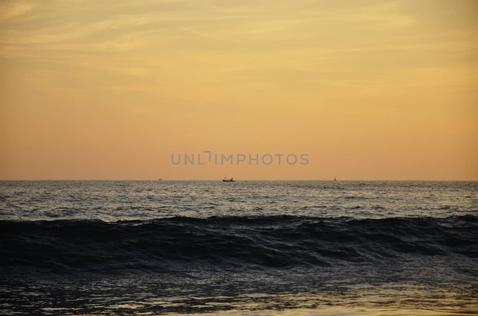 A ship sailing by at a distance in the Indian Ocean at Sunset