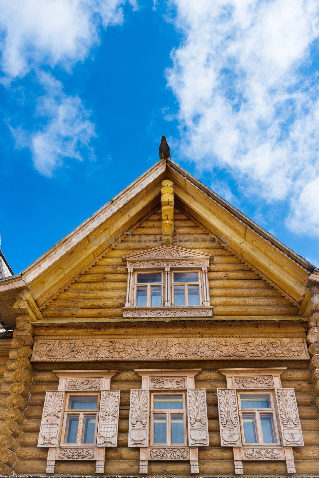 Wooden decorated windows in log house under blue sky, Russian traditional architecture.