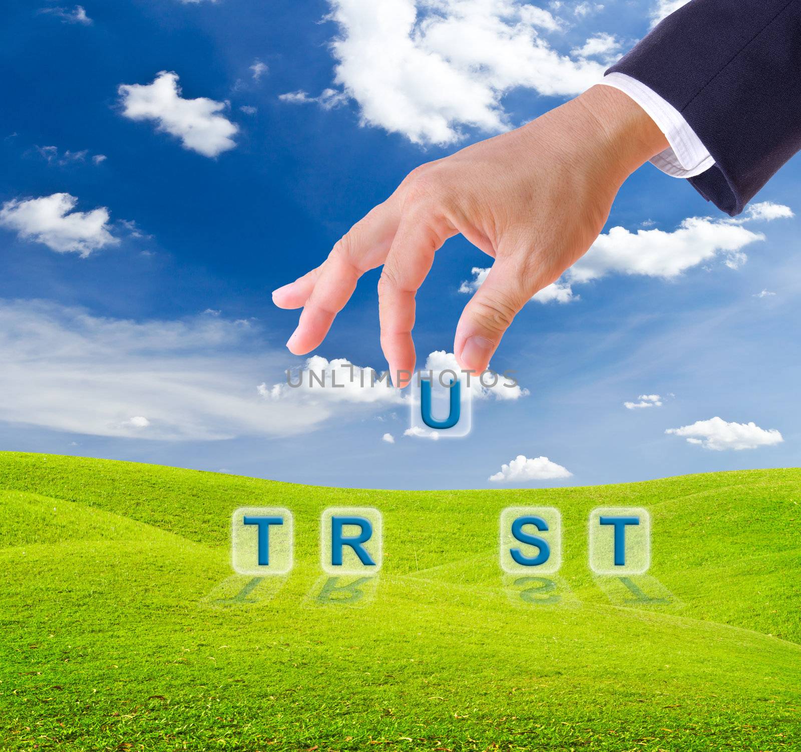 business man hand made trust word buttons on green grass meadow