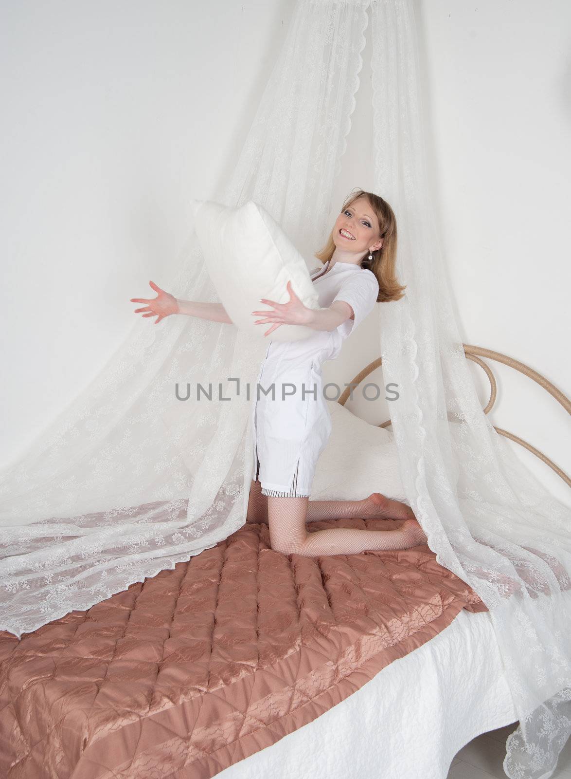 sexy woman doctor on the bed throwing pillows