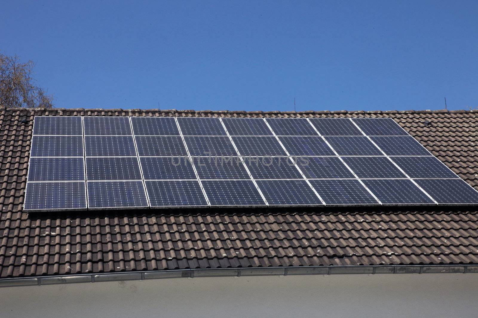An array of photovoltaic solar panels mounted on a house roof to supply renewable domestic electricity by converting the radiant energy of the sun