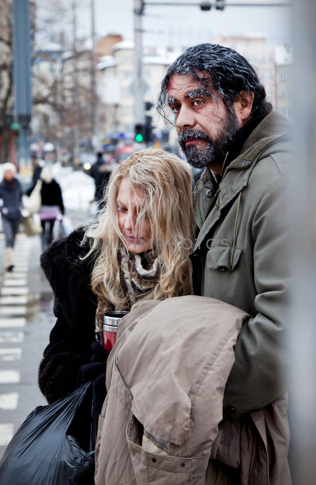 Homeless struggling couple embracing in city centre, freezing