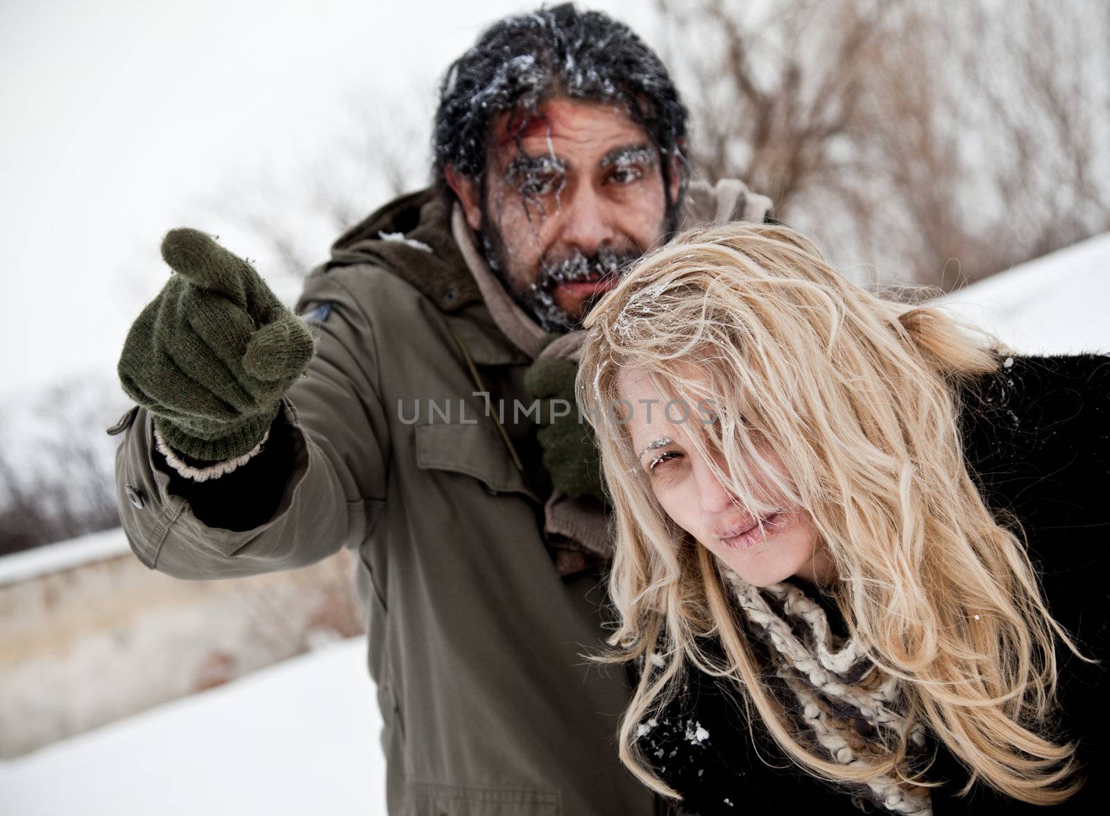 Homeless couple struggling in winter time, male pointing forward