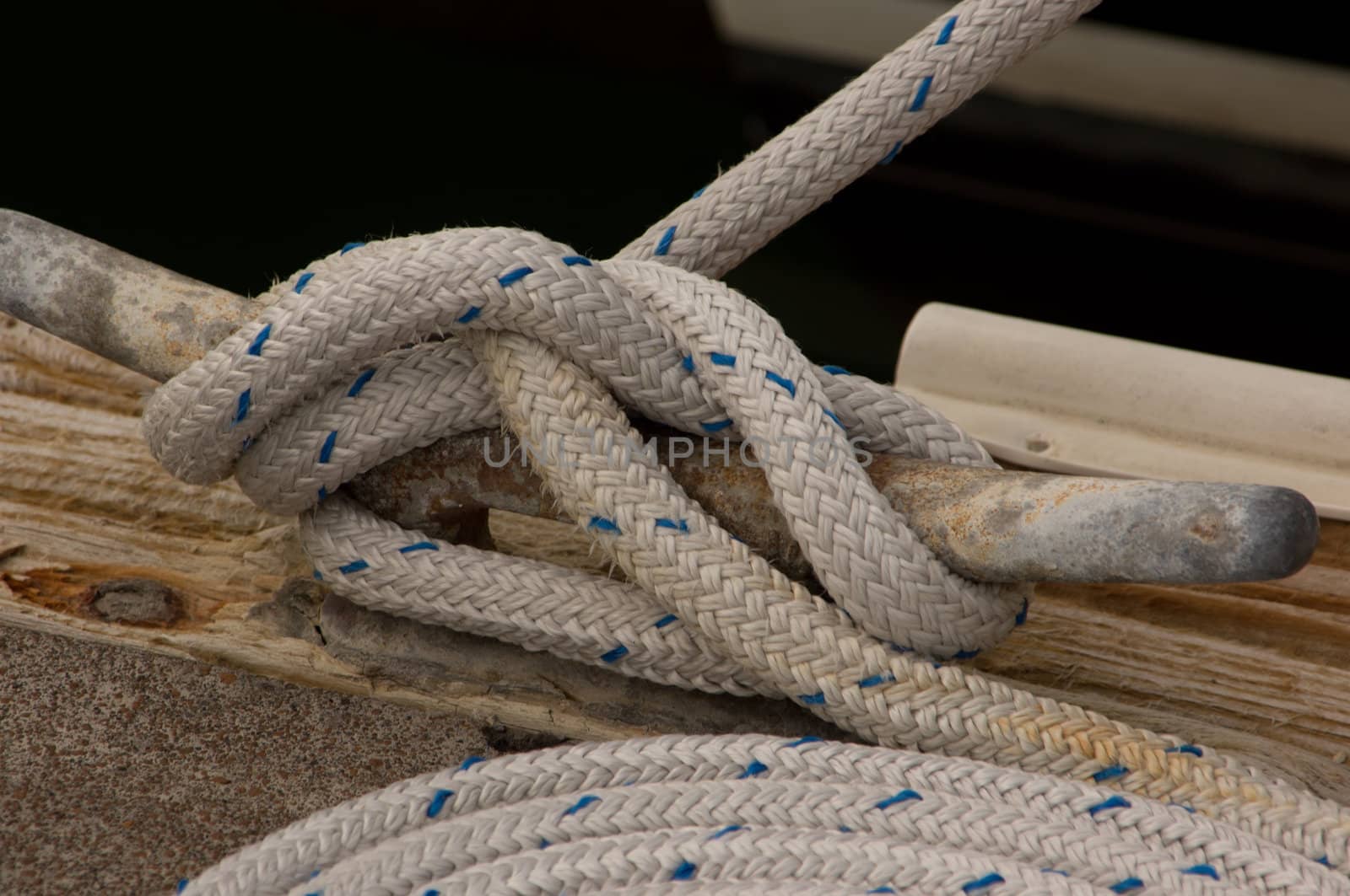Closeup view of boat rope tied to cleat on dock