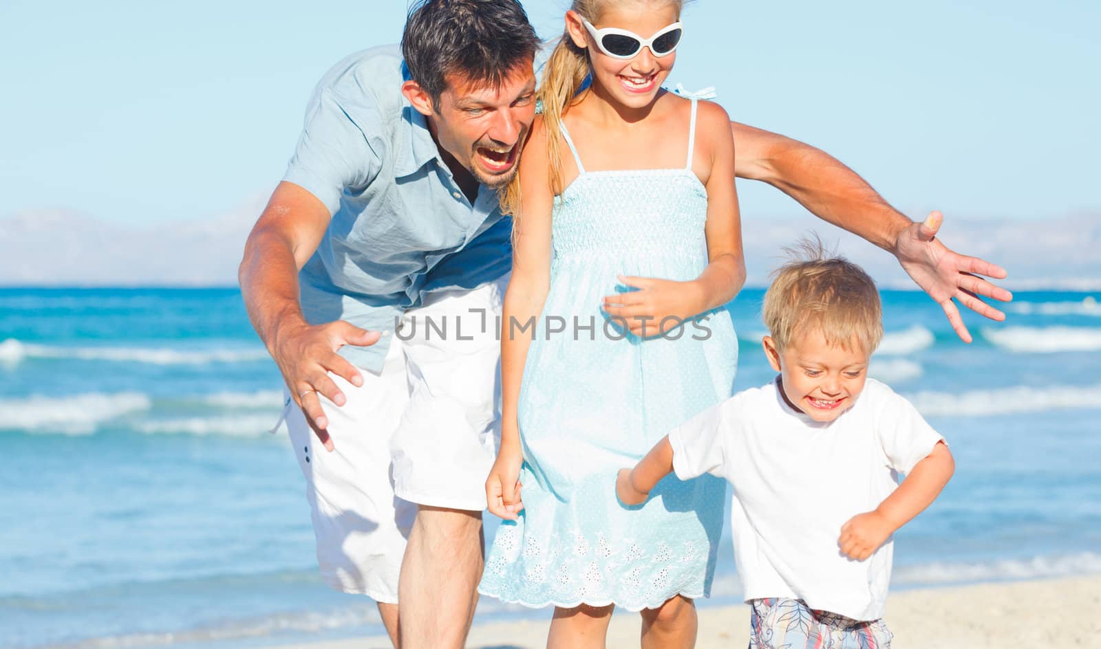 Happy family of three sitting and having fun on tropical beach