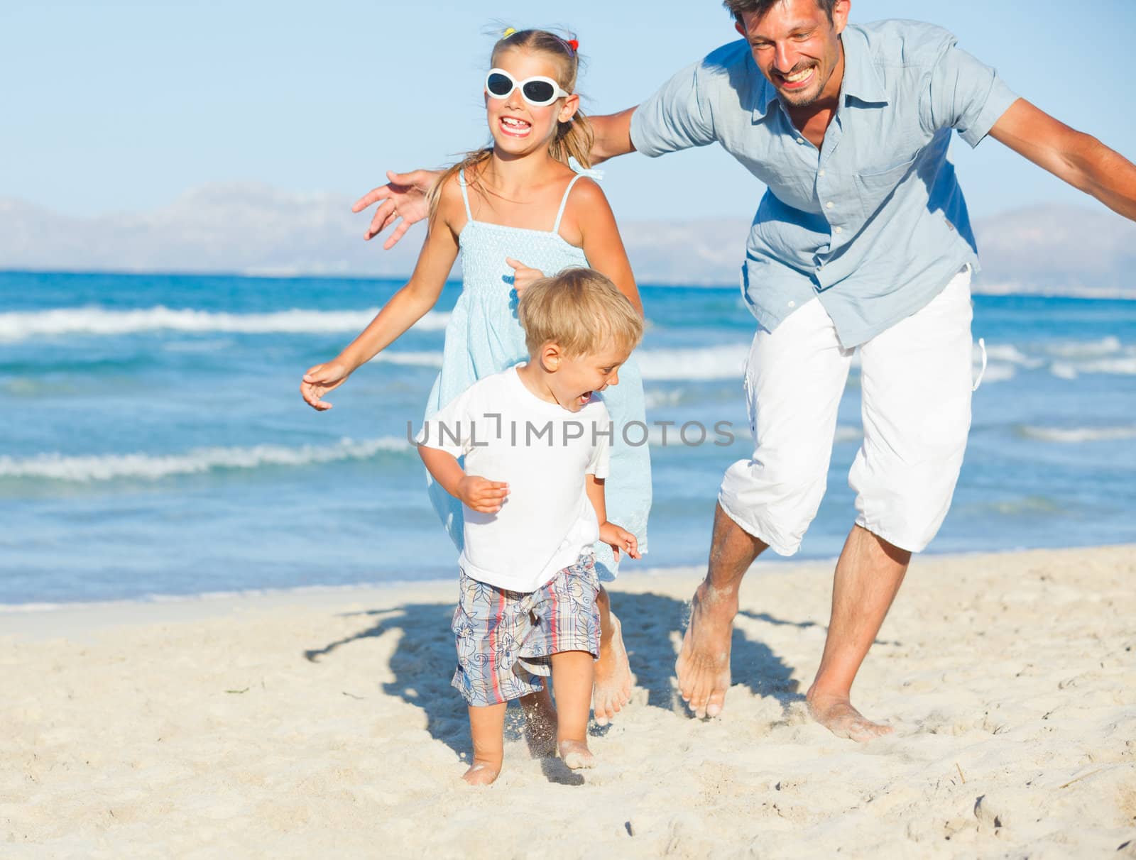 Happy family of three sitting and having fun on tropical beach