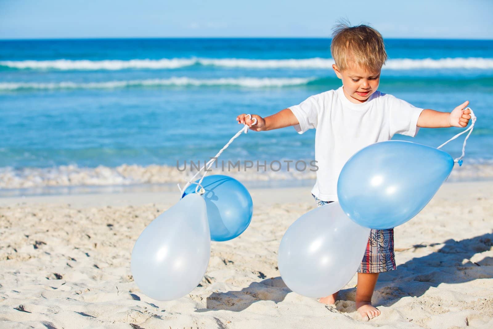 Cute little boy plays with ballons on the beach