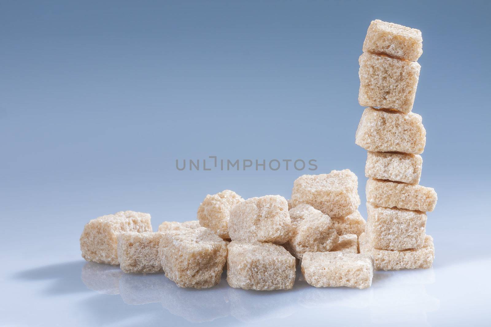 Vertical stack of brown sugar cubes on blue. Horizontal.