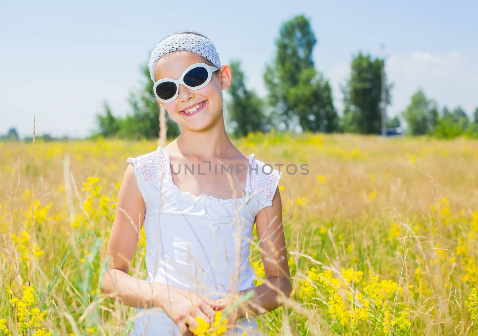 Adorable girl in glasses with flowers in yellow field. Summer freedom andjoy concept.