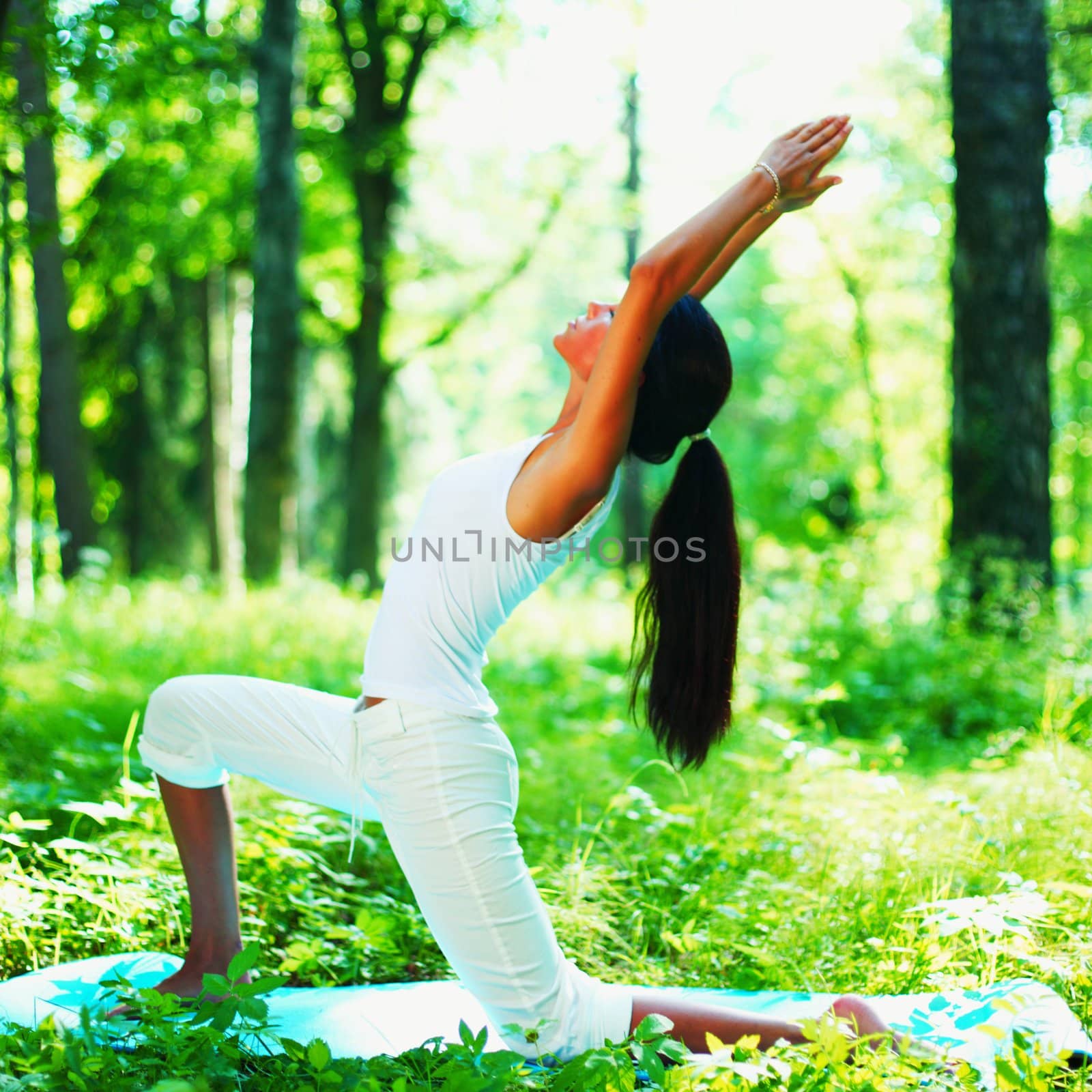 Young woman doing yoga exercise in green park by Yellowj